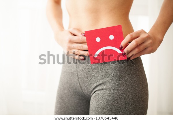 膣や尿の感染と問題のコンセプト 若い女は股の上に悲しげな笑みを浮かべて紙を持つ の写真素材 今すぐ編集