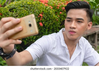 A Vain Young Man Takes A Selfie Of Himself While Sitting Down At The Garden.