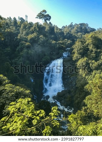 Valara Waterfall in Munnar, Kerala, India. This captivating photograph showcases the cascading waterfall, framed by towering mountains and embraced by lush trees.this image captures the untamed beauty