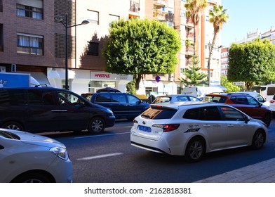 Valencia city street, road traffic, cars on road, people and buildings. Urban architecture, square, trees in parks and panarama.  Possible granularity, motion blur. Dec 15, 2021, Spain, Valencia.