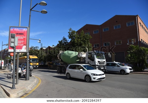 Valencia city street, road traffic, cars on\
road, people and buildings. Urban architecture, square, trees in\
parks and panarama. Car in motion on city streets. December 15,\
2021, Spain, Valencia.
