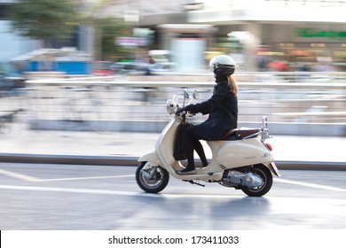 VALENCIA, SPAIN - JANUARY 27, 2014: A woman on a Vespa scooter traveling in the town center of Valencia with motion blur. Vespa is an Italian brand of scooter manufactured by Piaggio.