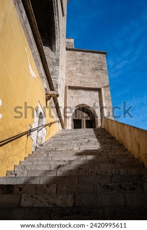 Valencia, Spain - May 12 2023 : Looking up the stairs of the Mediterranean Torres quart towers, a Valencia fortress with vibrant yellow and ancient brick walls. Vertical mobile friendly layout
