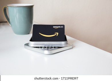 Valencia/Spain: 04.23.2020: Close Up Of A Amazon Spain Gift Card 2020 With Metallic Box. White Table And Cup Of Coffe. Concept Of E-commerce.