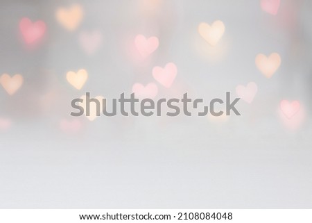 Photo of Valentine background mockup with pink and yellow heart shaped light bokeh on a grey seamless backdrop. Use for digital product mockup placement or as a background for text.