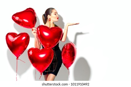 Valentine Beauty girl with red air balloon portrait pointing hand, isolated on white background. Beautiful Happy Young woman presenting products. Holiday party, birthday. Joyful model 