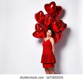 Valentine Beauty Mature Short Hair Woman In Red Cocktail Dress With Red Heart Air Balloons Behind Her Smiles Shyly Over White With Free Copy Space. Holiday Party.