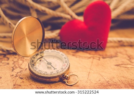 Valentine day background. Old compass on vintage map with red heart. Retro filter. Direction to real love of your heart concept.
