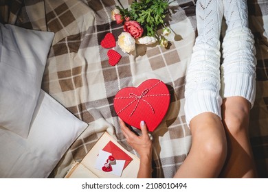 Valentine Day Celebration Flat Lay With Present In Heart-shaped Box And Womans Legs In White Socks On Bed Or Floor Background, Top View