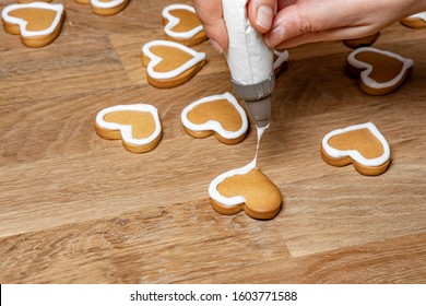 Valentine Day. Decorating Gingerbread Cookies With Icing. Woman Hands Decorate Cookies In Shape Of Heart.