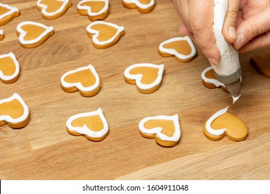 Valentine Day. Decorating Gingerbread Cookies With Icing. Woman Hands Decorate Cookies In Shape Of Heart.