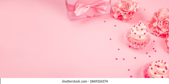Valentinstag Liebescupcakes mit Sahne und Herzen Rosenblumen und Geschenk auf rosafarbenem Hintergrund mit Kopienraum für Text