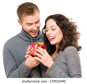 Valentine Gift. Happy Young Couple With Valentine's Day Present Isolated On A White Background. Happy Man Giving A Gift To His Girlfriend. Holiday