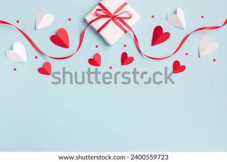Valentine or mother day festive composition with gift or present box and red hearts on pastel blue background top view. Flat lay style.