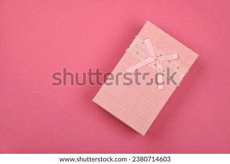 Valentine template of closed pastel pink gift box with ribbon chiffon bow over pink wrapping paper background, close up flat lay, elevated top view, directly above
