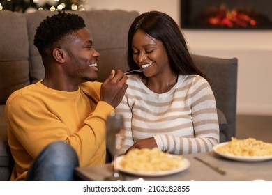 Valentine's Celebration. Loving African American Couple Having Romantic Dinner Eating Pasta, Boyfriend Feeding Girlfriend Flirting And Having Fun During Date At Home. Love And Romance Concept