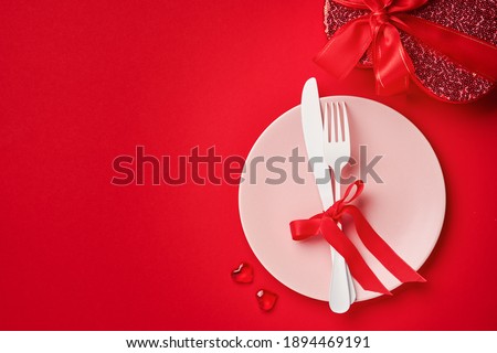 Valentines day background or concept with empty pink plate and whiteware on scarlet or red background. Top view flat lay with copy space.