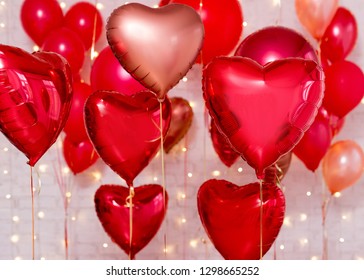 Valentine's day background - red foil heart shaped balloons over white brick wall
