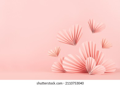 Valentines day background - stage with pink paper ribbed origami hearts soar on soft light pink color as border with copy space. Love mockup for advertising, design, presentation, card, poster, flyer.