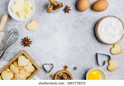 Valentine's Day baking culinary background. Ingredients for cooking on wooden kitchen table, baking recipe for pastry. Heart shape cookies. Top view. Flat lay.