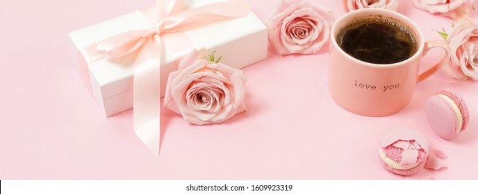 Valentine's day, birthday background banner. Pink cup of coffee, pink roses and pink macaroons on pink background. Copy space
