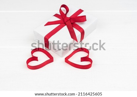 Valentine's Day or birthday concept with copy space. Two red ribbon heart and gift box on white wood