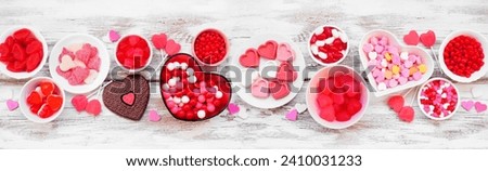 Valentines Day candy table scene with a variety of sweets. Above view on a white wood banner background.
