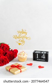 Valentine's Day Composition With Gift Box, Hearts, Red Roses, Cupcake And Wooden Calendar With The Date 14 February On White Background. Vertical, Copy Space. Greeting Card Mockup For Valentine's Day