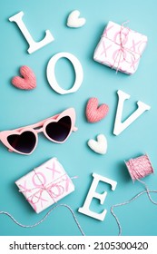 Valentines day composition with word love, sunglasses, gifts, hearts on blue background.