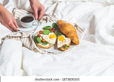 Valentine's Day Concept. Breakfast In Bed On Valentine's Day. Sandwiches With Croissant, Bagels, Cream Cheese And Fried Eggs Hearts On A White Bed Background.