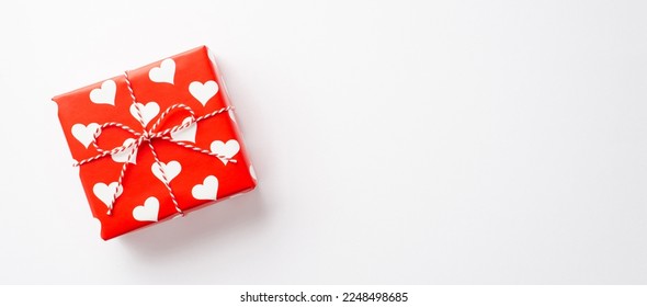 Valentine's Day concept. Top view photo of giftbox in wrapping paper with heart pattern on isolated white background with copyspace - Shutterstock ID 2248498685