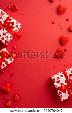 Valentine's Day concept. Top view vertical photo of gift boxes heart shaped candies candles and sprinkles on isolated red background with empty space