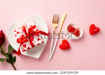 Valentine's Day concept. Top view photo of heart shaped plates giftbox knife fork candies rose and candles on isolated pastel pink background