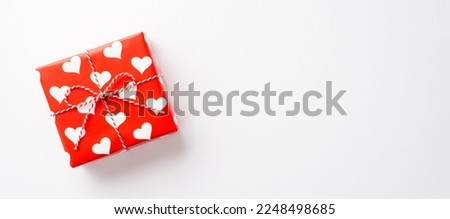 Valentine's Day concept. Top view photo of giftbox in wrapping paper with heart pattern on isolated white background with copyspace