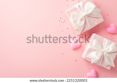 Valentine's Day concept. Top view photo of gift boxes with white ribbon bows heart shaped candles and golden sequins on isolated light pink background with copyspace