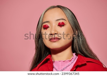 Valentines day concept, young asian woman with heart shaped eye makeup and closed eyes on pink