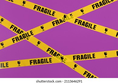 Valentines day creative layout with fragile warning printed roll tape on bright purple background. 80s or 90s retro fashion aesthetic love concept. Minimal romantic idea.