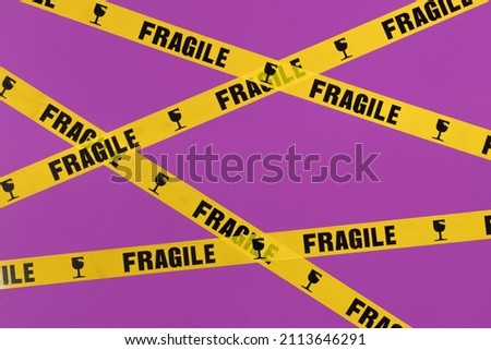 Valentines day creative layout with fragile warning printed roll tape on bright purple background. 80s or 90s retro fashion aesthetic love concept. Minimal romantic idea.