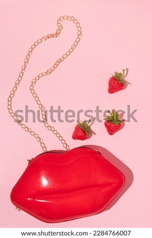 Valentines day creative layout lips shaped lady purse and strawberries on pastel pink background. 80s or 90s retro fashion aesthetic love concept. Minimal romantic cosmetic idea.