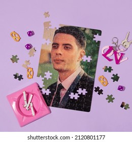 Valentines Day Creative Layout With Love Pendant For Keys, Pink Ashtray With Cigarette Leftovers And Puzzle Picture Of Man On Pastel Purple Background. 80s, 90s Retro Romantic Aesthetic Love Concept. 