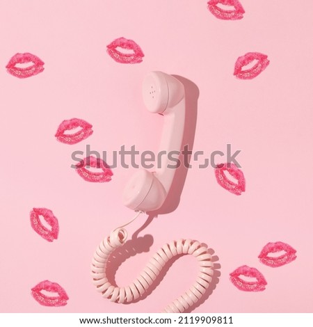 Valentines day creative layout with pink retro phone handset and kiss prints on pastel pink background. 80s, 90s retro fashion aesthetic telephone and kiss concept. Minimal romantic communication idea