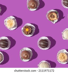 Valentines day creative pattern with chocolate pralines on bold purple background. 80s or 90s retro fashion aesthetic love and sweets concept. Minimal romantic idea chocolate.