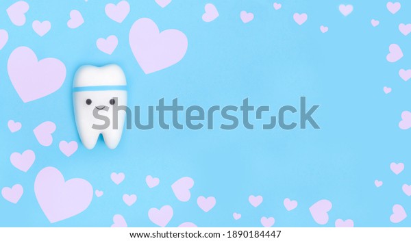 Valentine\'s day dentistry background\
banner. Tooth model on blue background with copy\
space