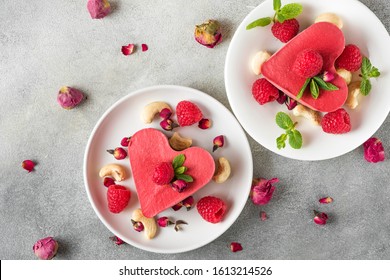 Valentines Day Dessert. Heart Shaped Raw Vegan Red Cakes With Raspberries, Dried Rose Flowers And Mint. Healthy Delicious Food. Top View. Love Concept