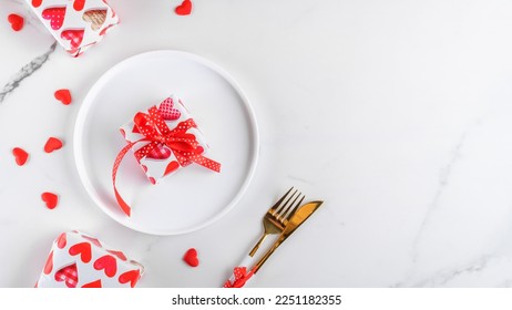 Valentines day dinner background with gifts, red hearts, fork and knife on white marble. Romantic holiday table setting. Festive table setting on white. Top view, flat lay. copy space, web banner - Shutterstock ID 2251182355