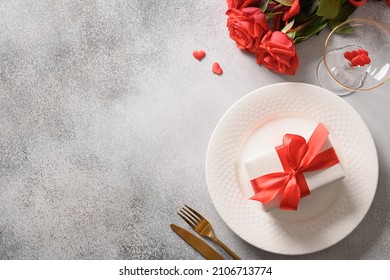 Valentine's day dinner with red roses, romantic gift and red roses on gray background. View from above. Copy space.