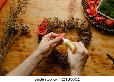 Valentines Day DIY Decoration, Spring Home Decor Crafts. Female Hands Glue Flowers On Heart Shaped Floral Wreath.