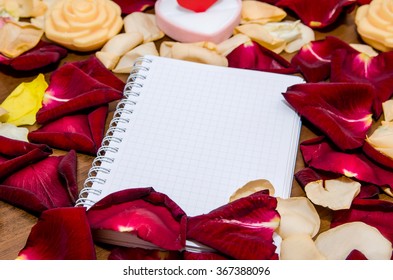 valentines day - empty notepad and gift box with many rose petals. Top view