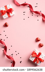 Valentines day flat lay composition with red ribbon, gifts, confetti on pink background. Suitable for vertical banner, flyer, brochure, stories on social media