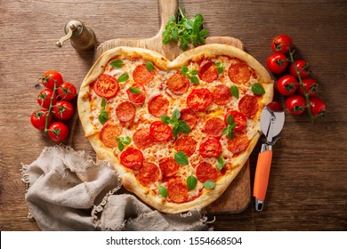 Valentines Day Food. Heart Shapped Pepperoni Pizza With Green Basil On Wooden Table, Top View